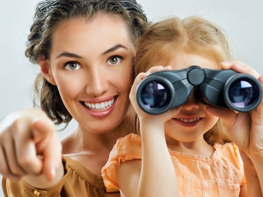 Foto de una mujer, o una madre, con una niña, o su hija, usando los mejores prismáticos para niños.
