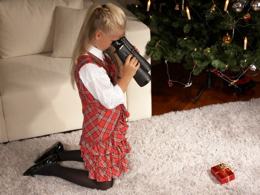 Foto de una niña mirando un regalo con unos prismáticos.