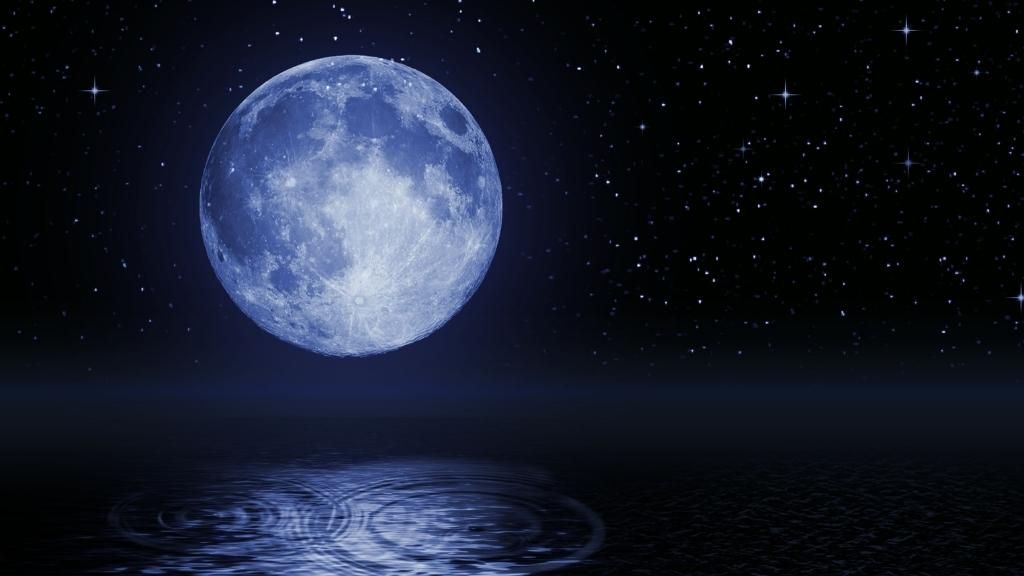 Foto de la Luna llena en la oscuridad de la noche sobre el mar y con un fondo estrellado. En este artículo haciendo referencia a la superluna de esturión.